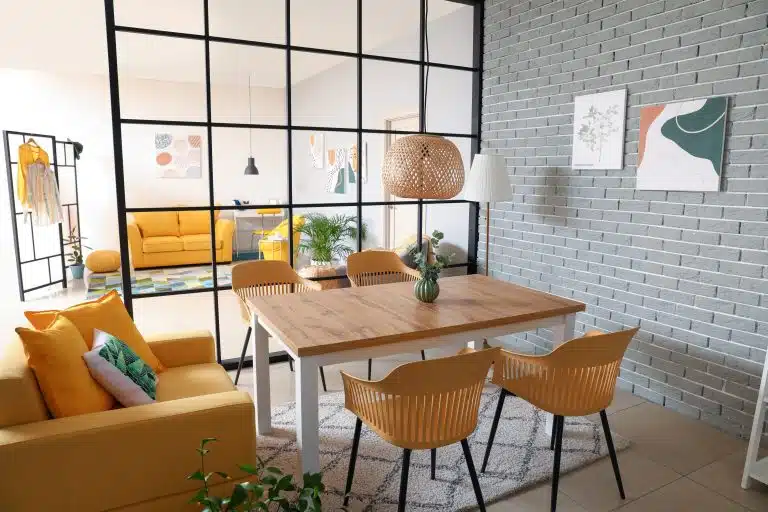 Dining area with a wooden table, yellow sofa and glass partition